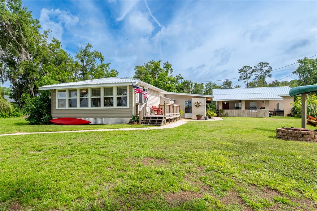 A tan house with a metal roof, a wooden deck, and a red kayak outside — 6600 SW 160TH STREET, STARKE, FL