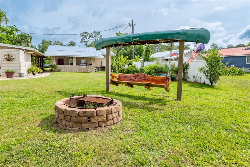 A backyard features a stone fire pit and a wooden swing topped by a canoe — 6600 SW 160TH STREET, STARKE, FL