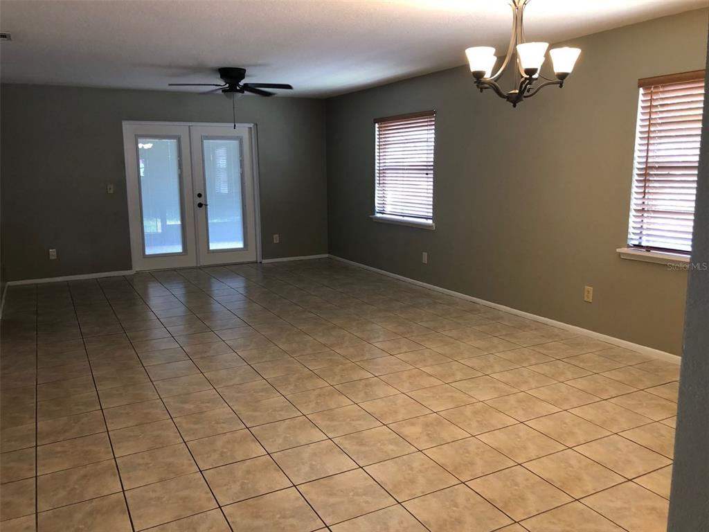 A galley kitchen features light wood cabinets, stainless steel appliances, and white tile flooring — 625 E 8TH AVENUE, MOUNT DORA, FL