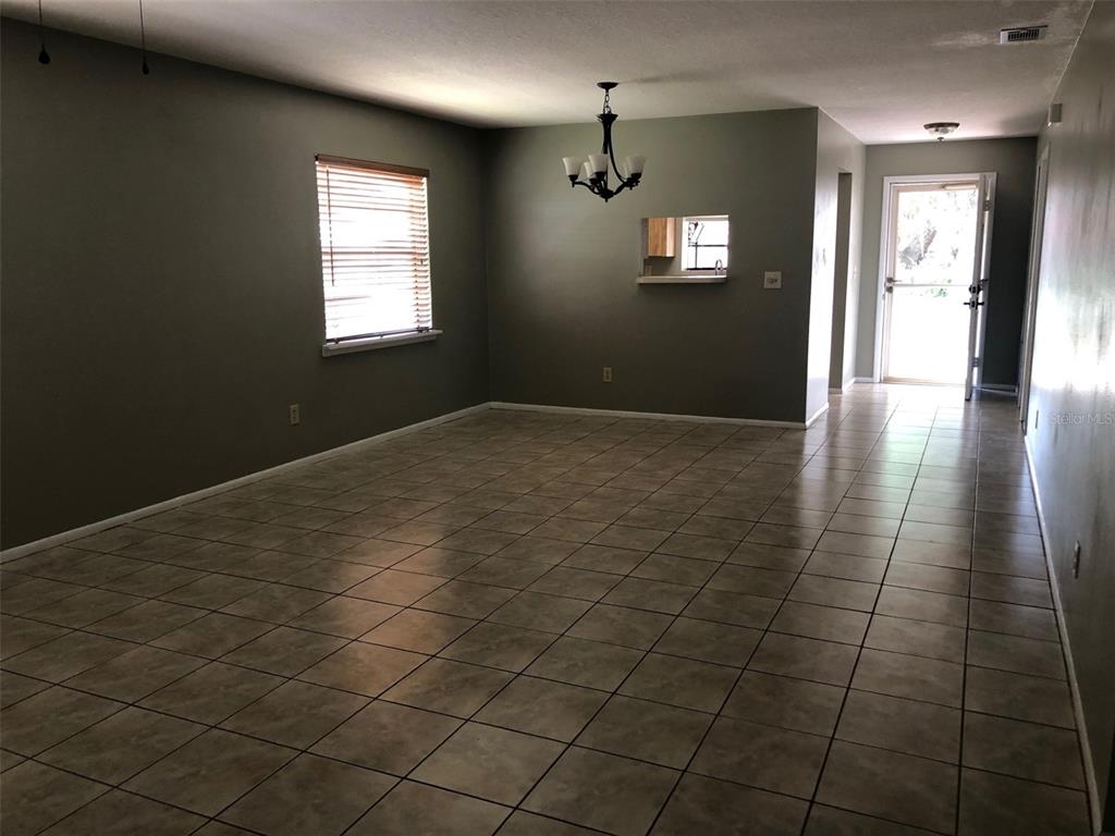A galley kitchen features light wood cabinets, stainless steel appliances, and beige tile flooring — 625 E 8TH AVENUE, MOUNT DORA, FL