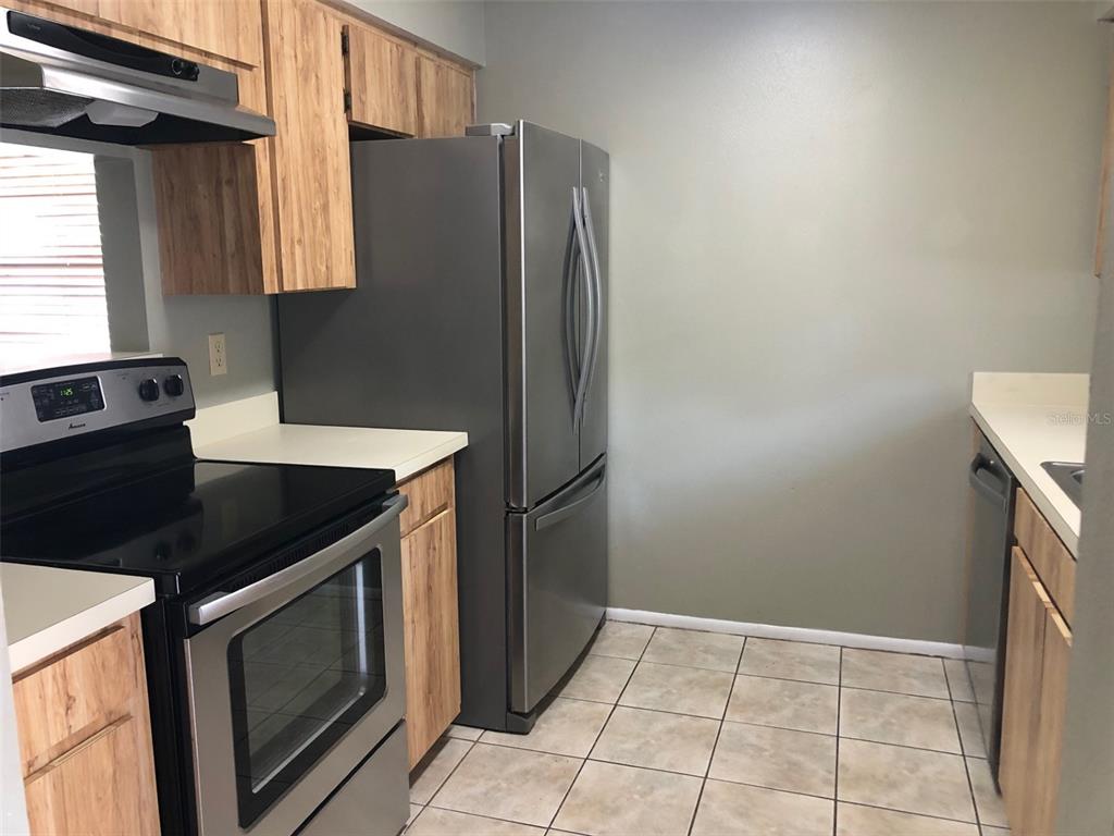 A kitchen sink with a stainless steel faucet sits below a window between wooden cabinets — 625 E 8TH AVENUE, MOUNT DORA, FL