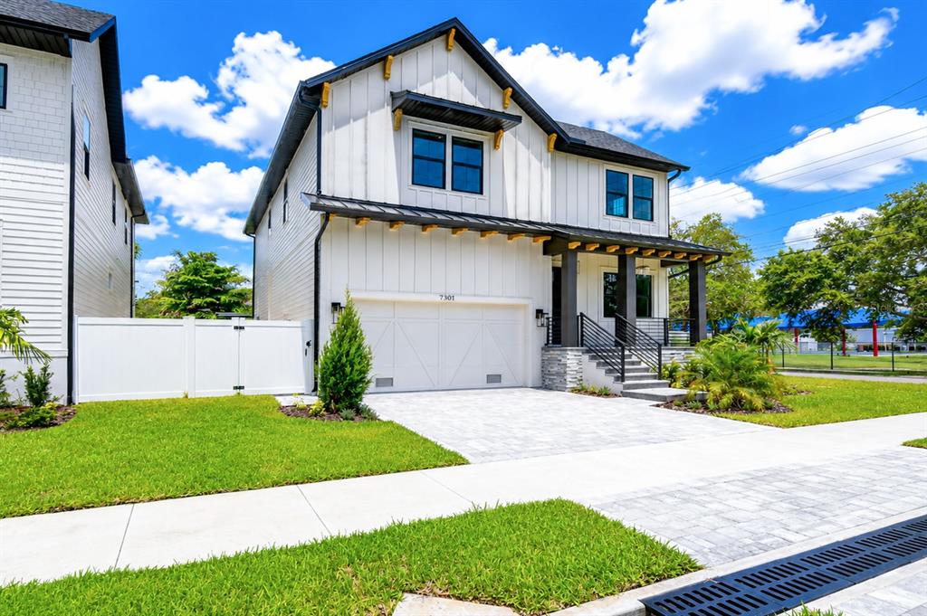 A two-story modern farmhouse with white vertical siding, a two-car garage, and a front porch — 7301 S FITZGERALD STREET, TAMPA, FL