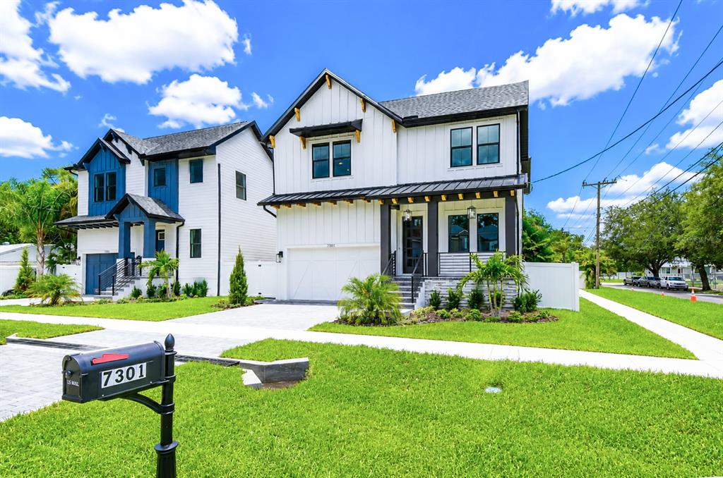 Two modern white houses with black trim and roofs stand on a grassy suburban lot — 7301 S FITZGERALD STREET, TAMPA, FL