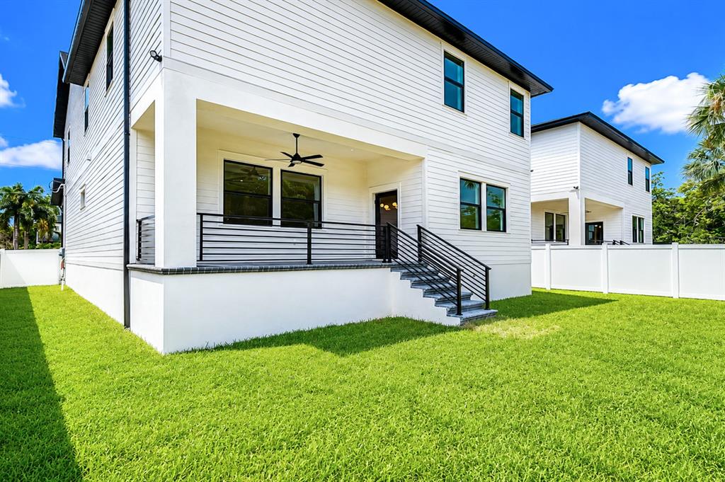 The exterior of a two-story white house features a covered patio with black railings — 7301 S FITZGERALD STREET, TAMPA, FL