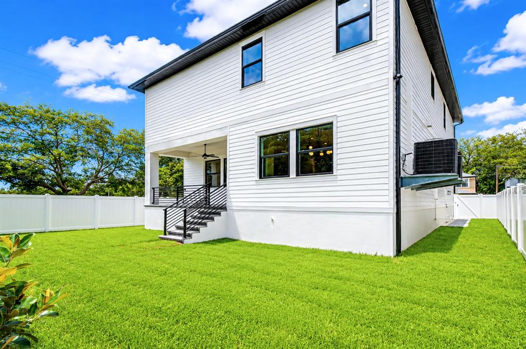 The exterior of a two-story white house features a covered porch with stairs and lawn — 7301 S FITZGERALD STREET, TAMPA, FL