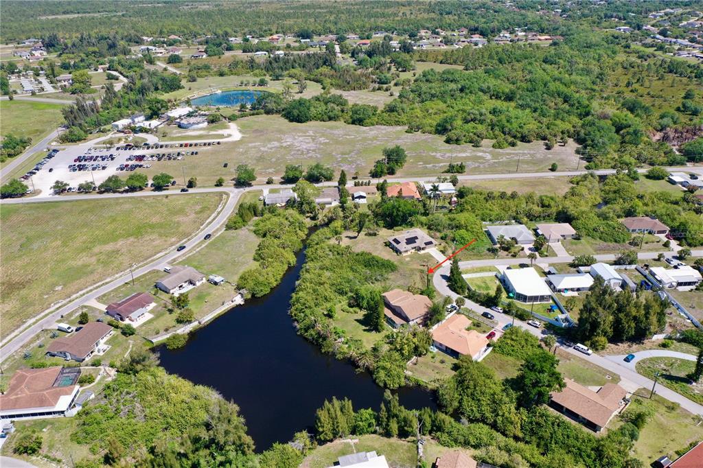 An aerial view shows a residential neighborhood with houses situated near a large pond — MONZA AVENUE, NORTH PORT, FL