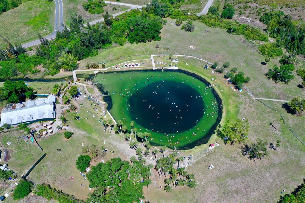 Aerial view of a circular natural spring surrounded by grassy parkland and a paved walkway — MONZA AVENUE, NORTH PORT, FL