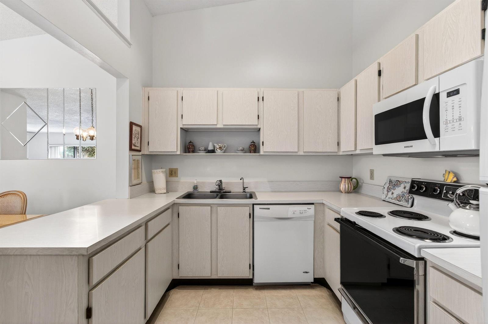 A kitchen features light wood cabinets, white appliances, and a double sink with tiled flooring — 3814 Coco Loba Lane, Boynton Beach FL 33436, BOYNTON BEACH, FL