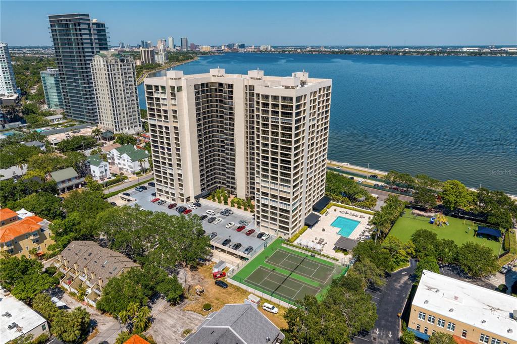 An aerial view shows a high-rise apartment building with a tennis court and swimming pool — 3301 BAYSHORE BOULEVARD UNIT 1601E, TAMPA, FL