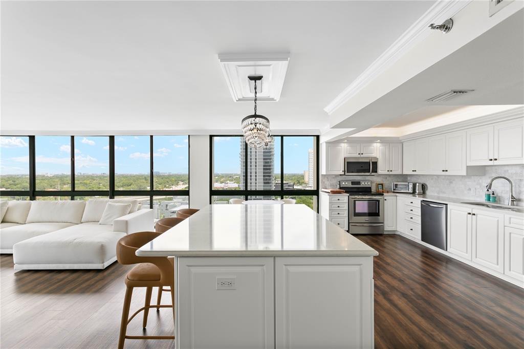 A modern kitchen with a white island and cabinetry overlooks a living area and city — 3301 BAYSHORE BOULEVARD UNIT 1601E, TAMPA, FL