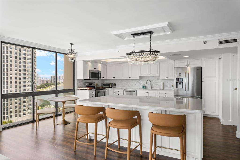 A kitchen features white cabinetry, a large island with tan stools, and floor-to-ceiling windows — 3301 BAYSHORE BOULEVARD UNIT 1601E, TAMPA, FL