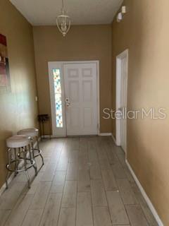 An entryway with light wood-look tile flooring, tan walls, a white front door, and barstools — 1142 BLUEGRASS DRIVE, GROVELAND, FL