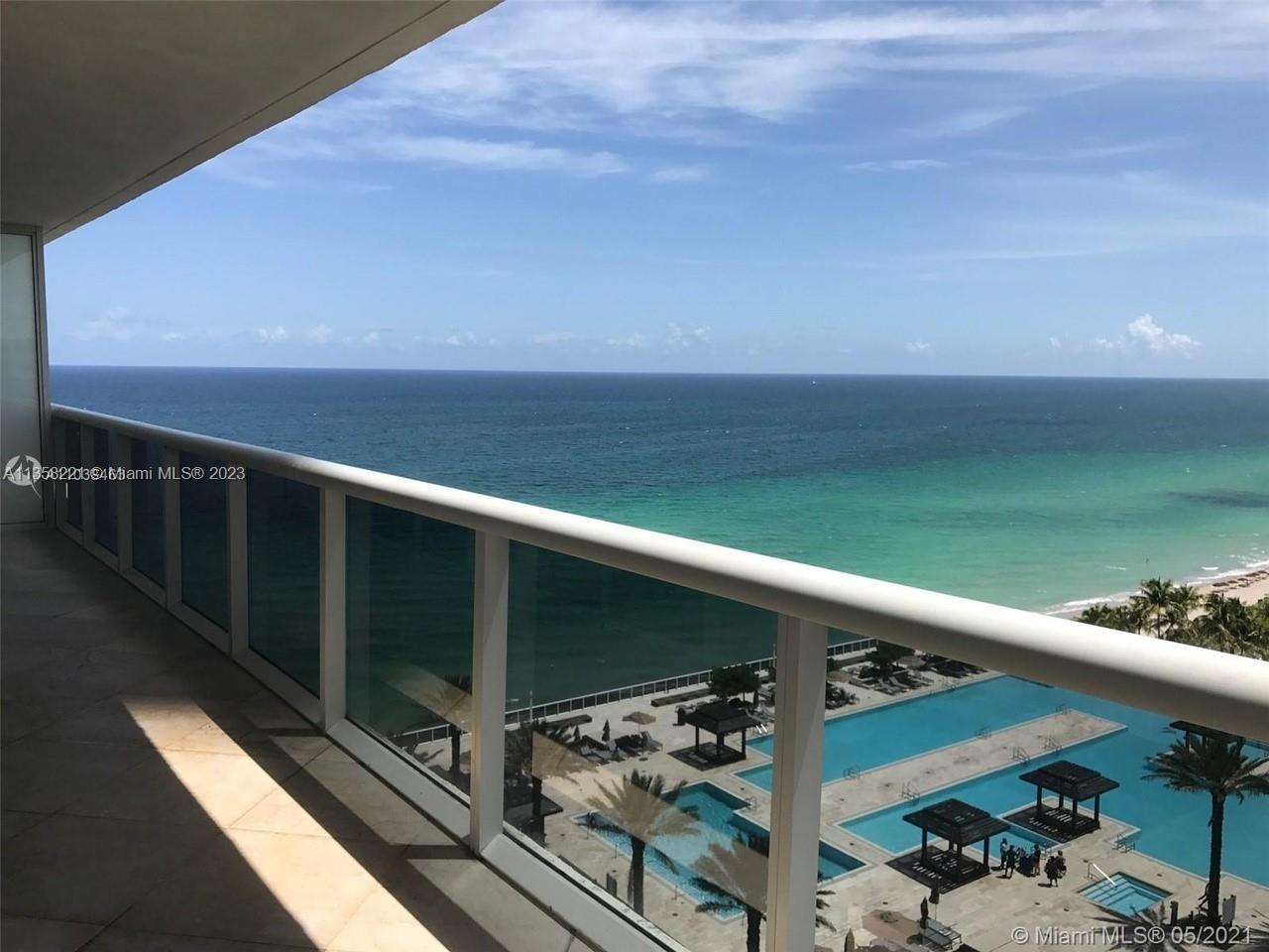 A balcony overlooks a swimming pool area and the ocean under a blue sky — 1830 S Ocean Dr # 1706, Hallandale Beach FL 33009, HALLANDALE BEACH, FL