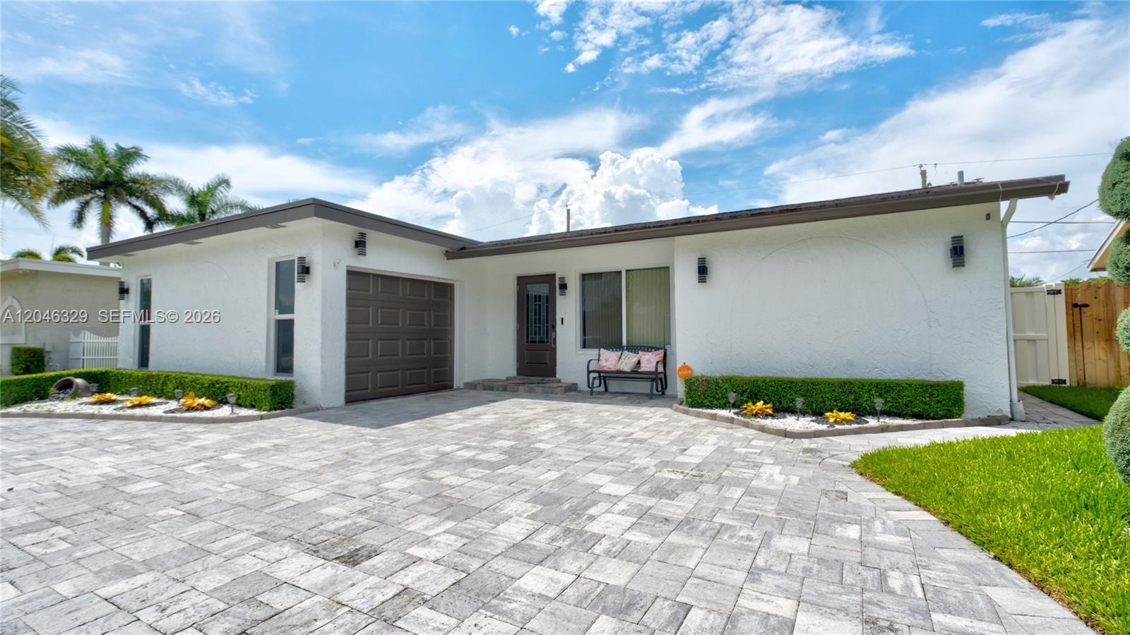 A single-story white house features a brown garage door, a paved driveway, and landscaping — 11370 NW 46th Pl, Sunrise FL 33323, SUNRISE, FL