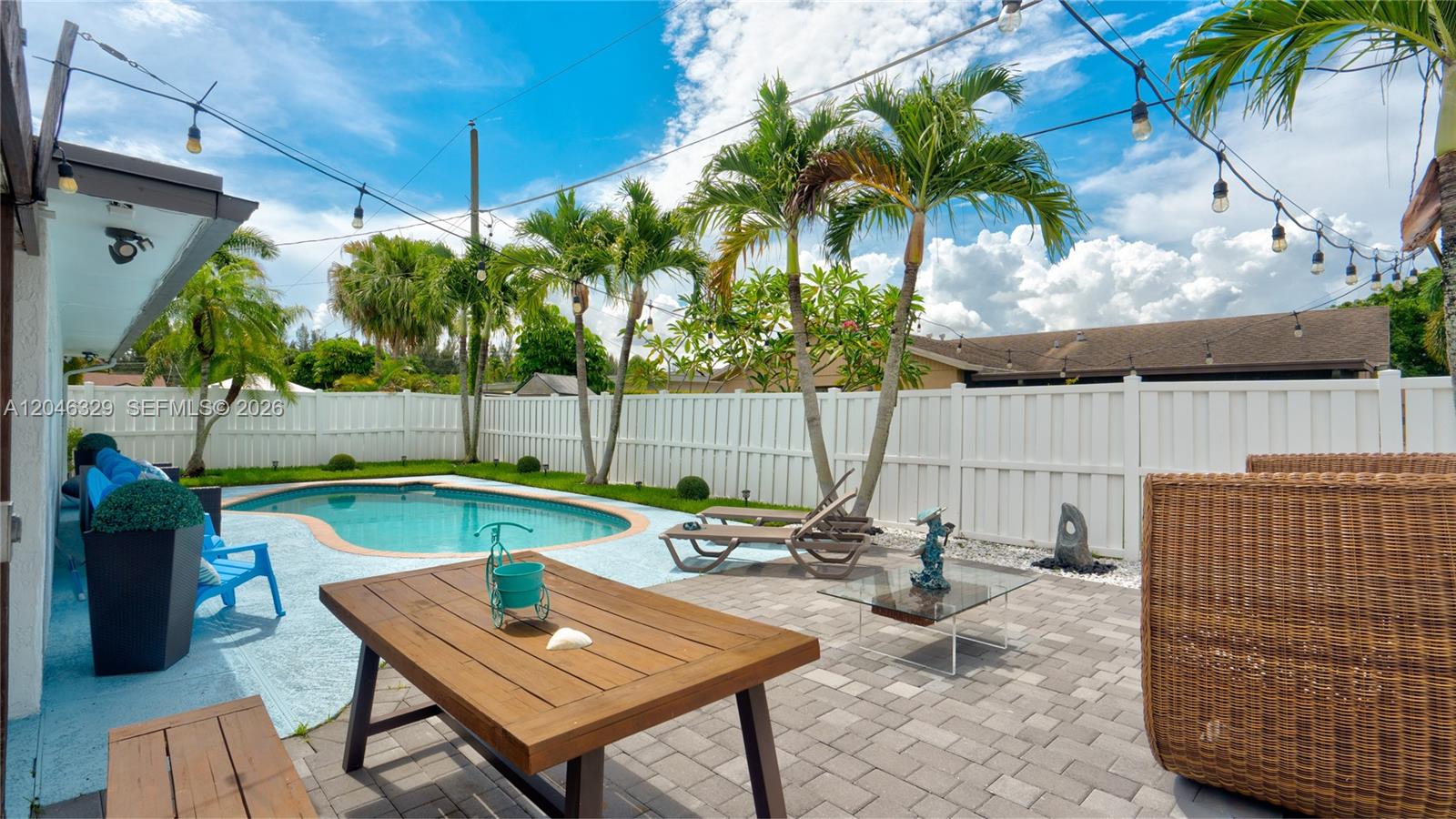 A backyard features a swimming pool, patio furniture, palm trees, and a white privacy fence — 11370 NW 46th Pl, Sunrise FL 33323, SUNRISE, FL