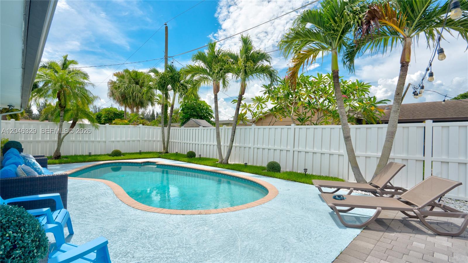 A backyard features a kidney-shaped swimming pool, lounge chairs, and palm trees by a fence — 11370 NW 46th Pl, Sunrise FL 33323, SUNRISE, FL