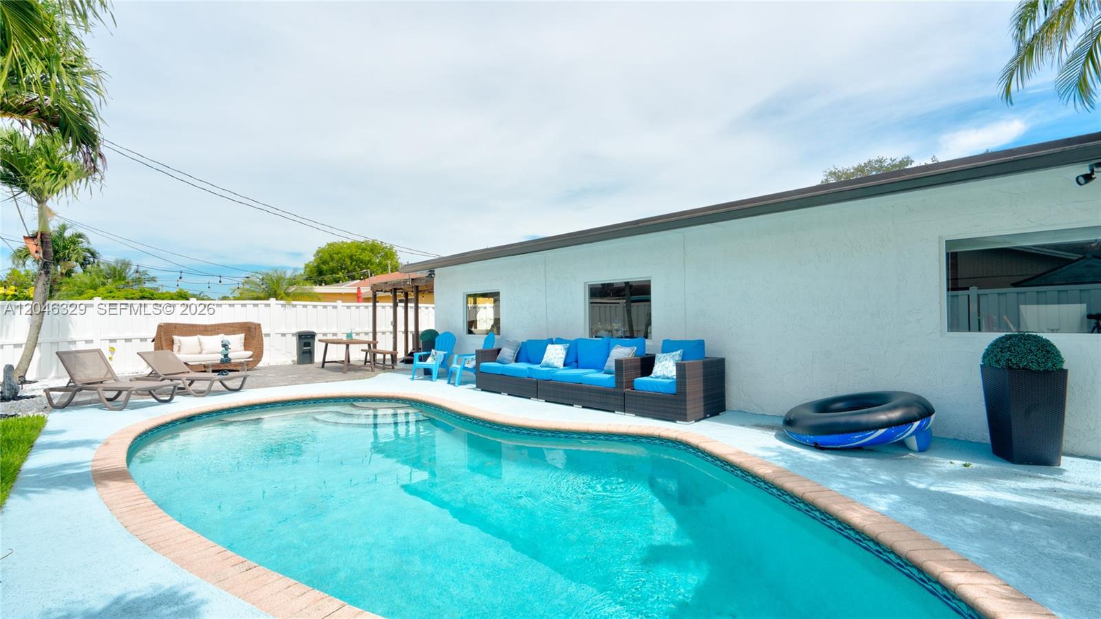 A backyard swimming pool features a patio with outdoor furniture and a white fence — 11370 NW 46th Pl, Sunrise FL 33323, SUNRISE, FL