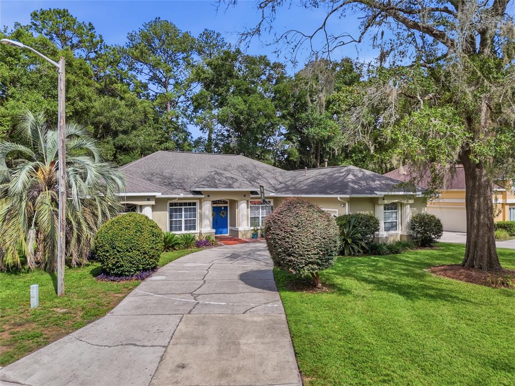 A single-story house with a blue front door, concrete driveway, and mature landscaping — 2015 NW 89TH DRIVE, GAINESVILLE, FL