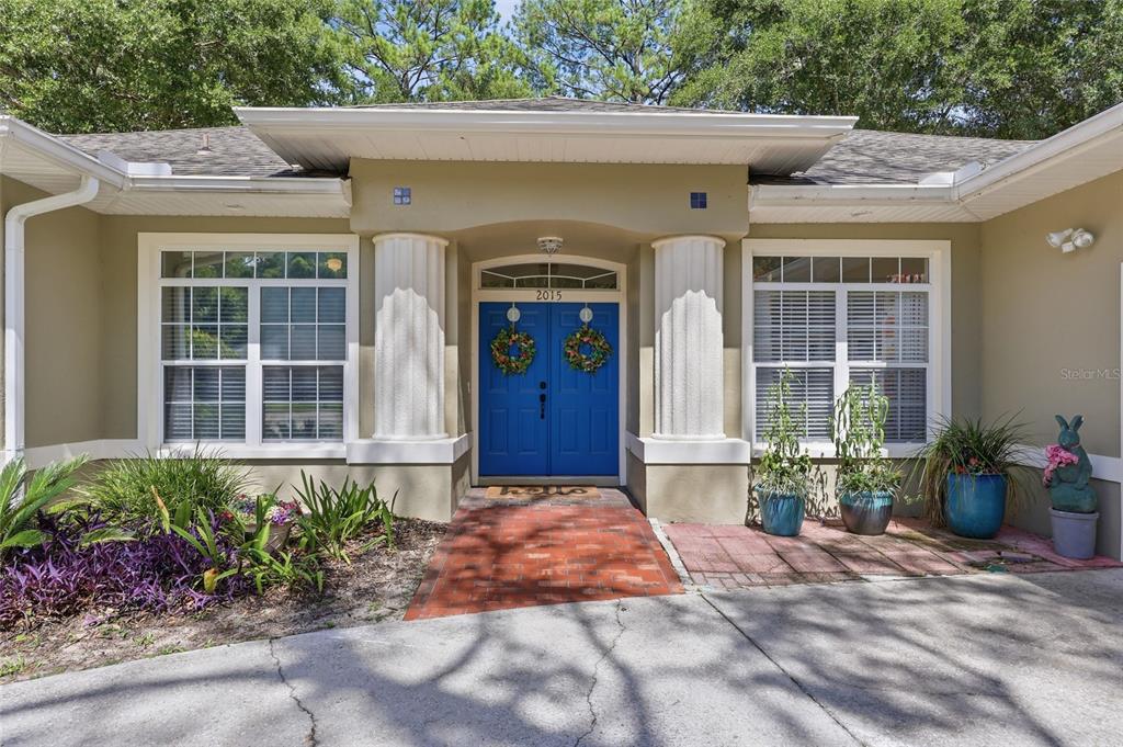 The exterior of a house features a blue double front door flanked by white columns — 2015 NW 89TH DRIVE, GAINESVILLE, FL