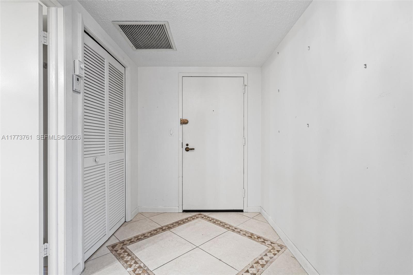 An entryway features white walls, a louvered closet door, and a tiled floor with a decorative border — 7200 Radice Ct # 709, Lauderhill FL 33319, LAUDERHILL, FL