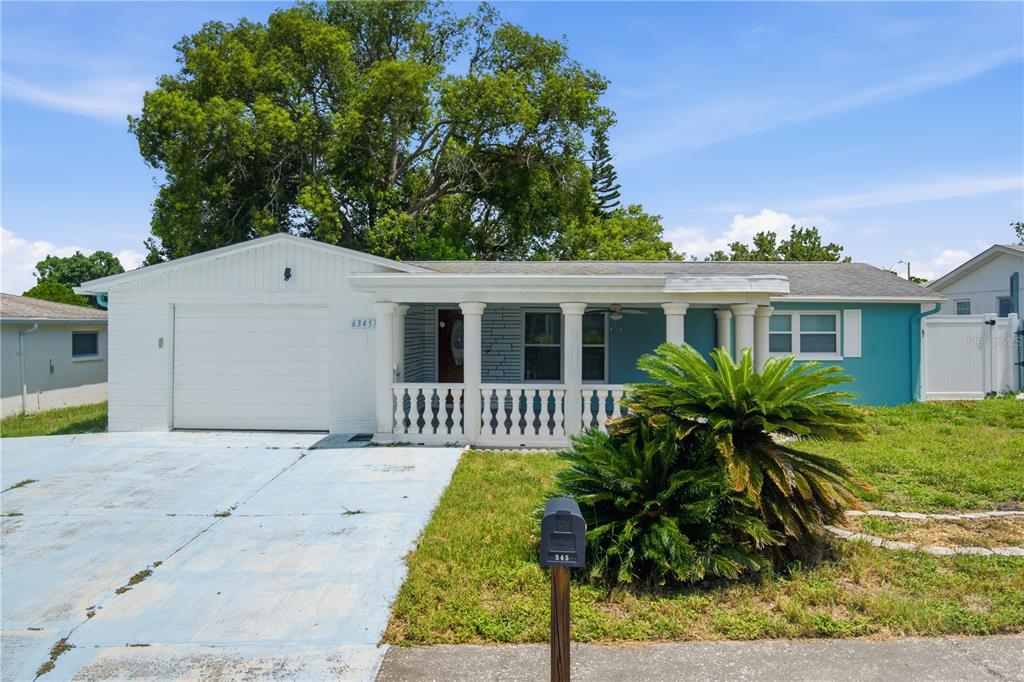 A single-story house with a white garage, a front porch with columns, and teal siding — 6345 PATELLA AVENUE, NEW PORT RICHEY, FL