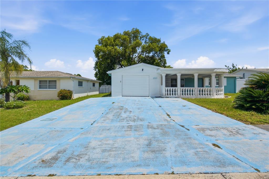 A single-story house with a white garage, a front porch, and a blue-painted concrete driveway — 6345 PATELLA AVENUE, NEW PORT RICHEY, FL