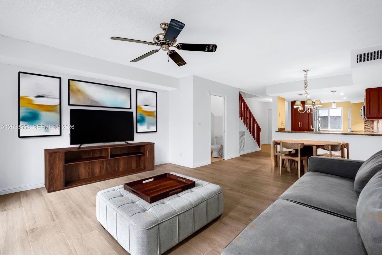 A living room with light wood floors, a grey sofa, and an open kitchen area — 7050 SW 42nd Ct, Davie FL 33314, DAVIE, FL