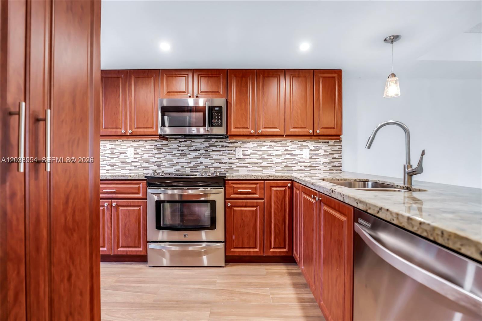 A kitchen features cherry wood cabinets, stainless steel appliances, and a granite countertop — 7050 SW 42nd Ct, Davie FL 33314, DAVIE, FL