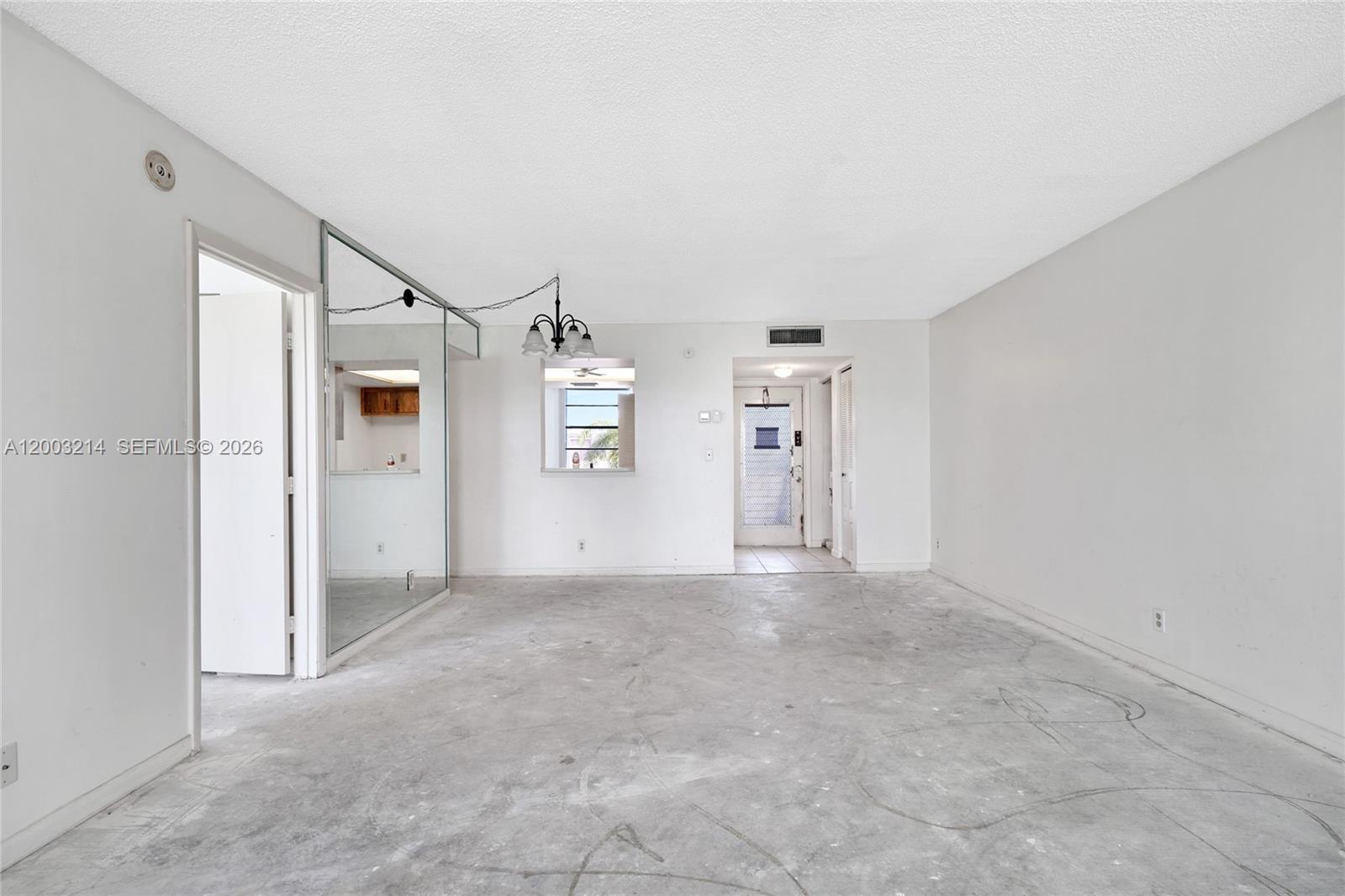 An empty room with concrete floors, a mirrored wall, and a view into a kitchen — 7330 NW 18th St # 204, Margate FL 33063, MARGATE, FL