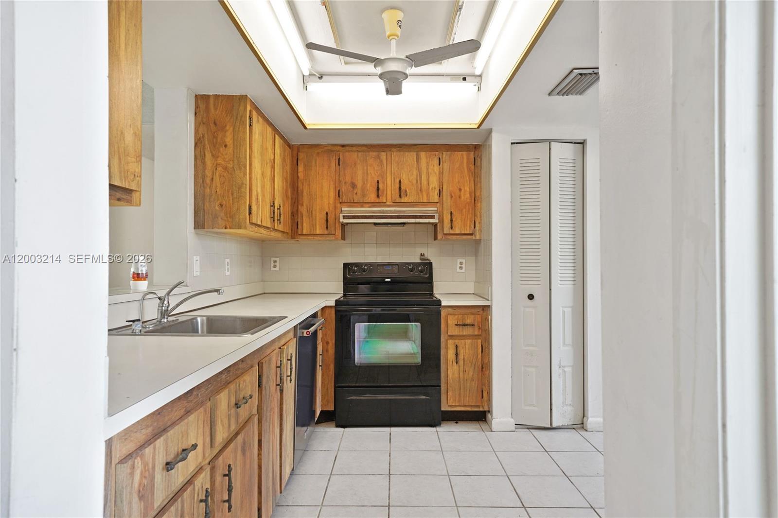 A kitchen features wood cabinets, a black stove, white countertops, and a ceiling fan — 7330 NW 18th St # 204, Margate FL 33063, MARGATE, FL