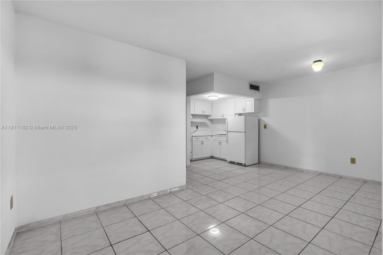 A kitchen with white cabinets and appliances opens into a tiled dining area — 1330 W 54th St # 302C, Hialeah FL 33012, HIALEAH, FL