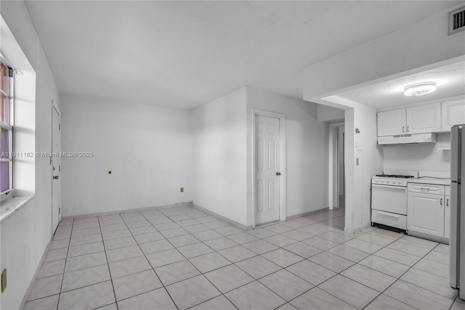 A kitchen and dining area features white cabinets, white appliances, and light-colored tiled flooring — 1330 W 54th St # 302C, Hialeah FL 33012, HIALEAH, FL
