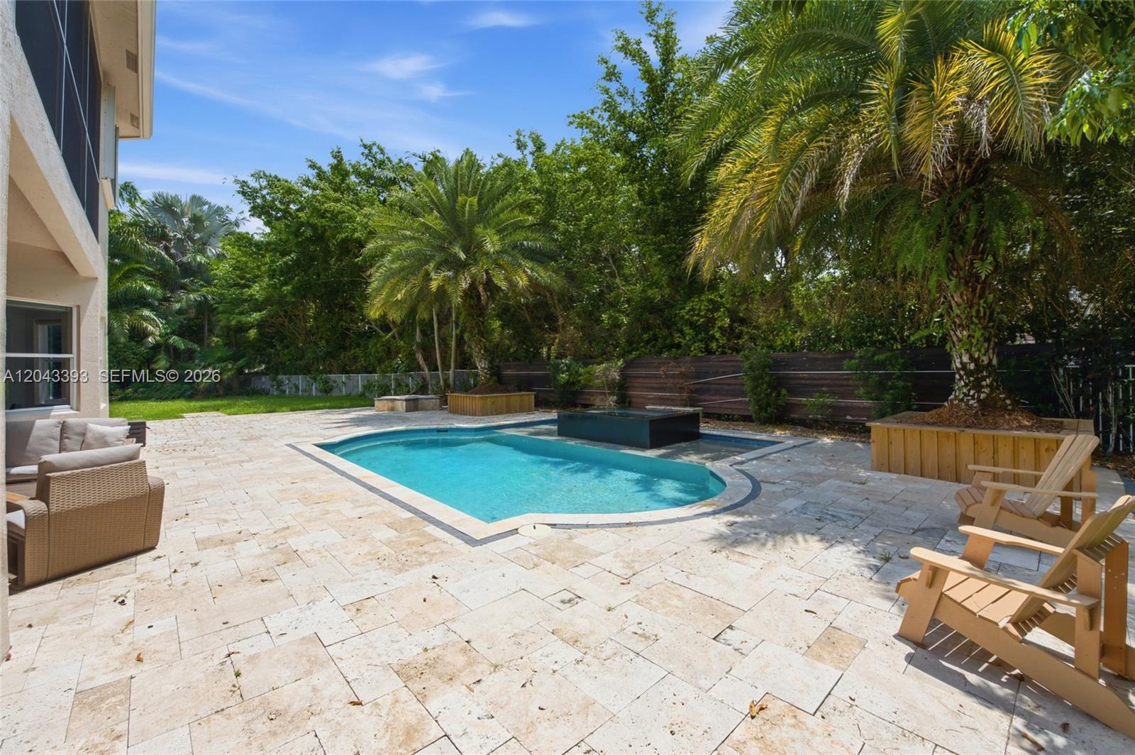 A backyard features a swimming pool, stone patio, wooden planters, and lounge chairs — 1585 Victoria Isle Way, Weston FL 33327, WESTON, FL