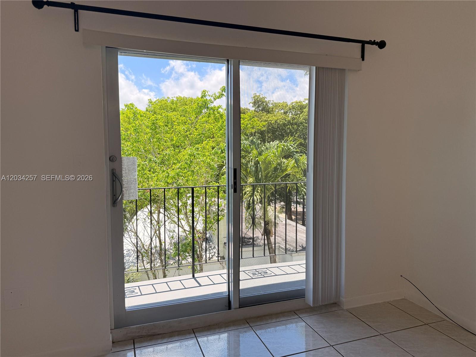 A sliding glass door leads to a balcony overlooking trees and a neighboring roof — 1860 SW 22nd St # 11, Miami FL 33145, MIAMI, FL