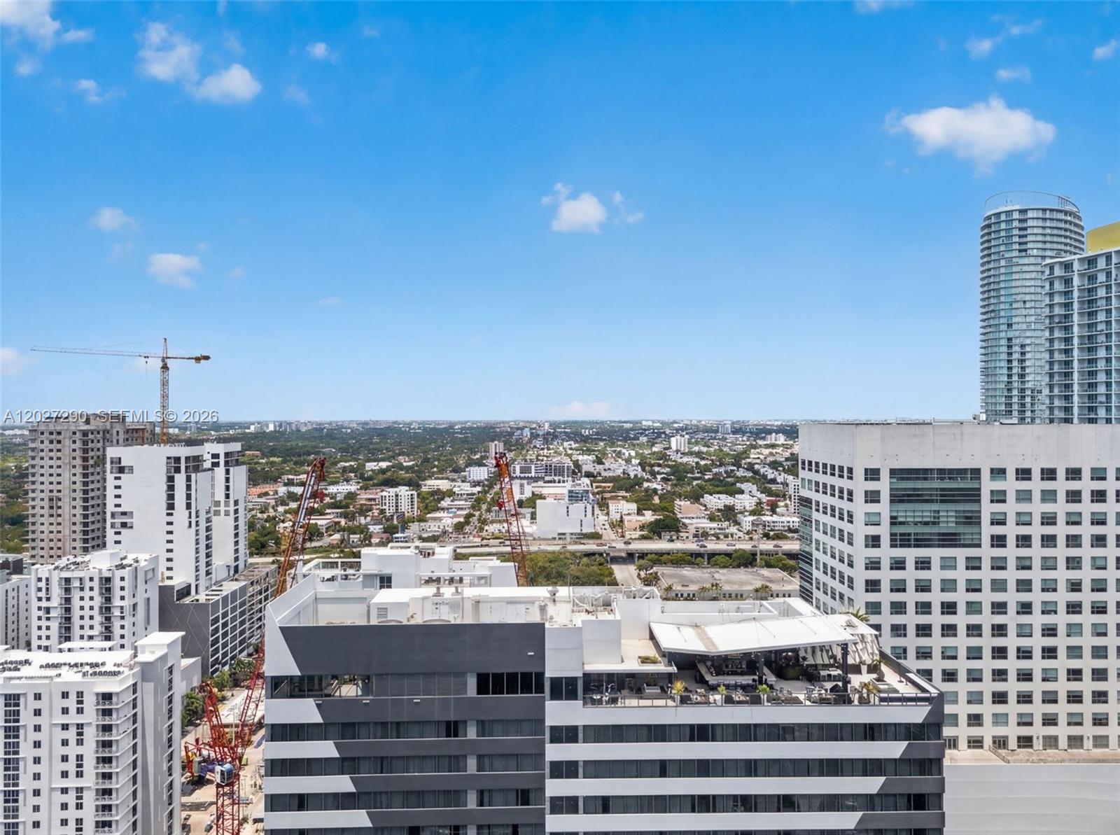 An elevated view of a city skyline featuring several high-rise buildings and construction cranes — 88 SW 7th St # 2408, Miami FL 33130, MIAMI, FL