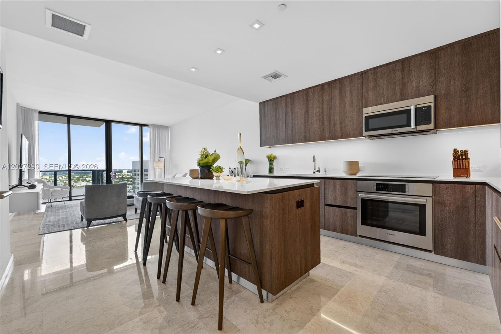 A modern kitchen features dark wood cabinetry, stainless steel appliances, and a white island — 88 SW 7th St # 2408, Miami FL 33130, MIAMI, FL