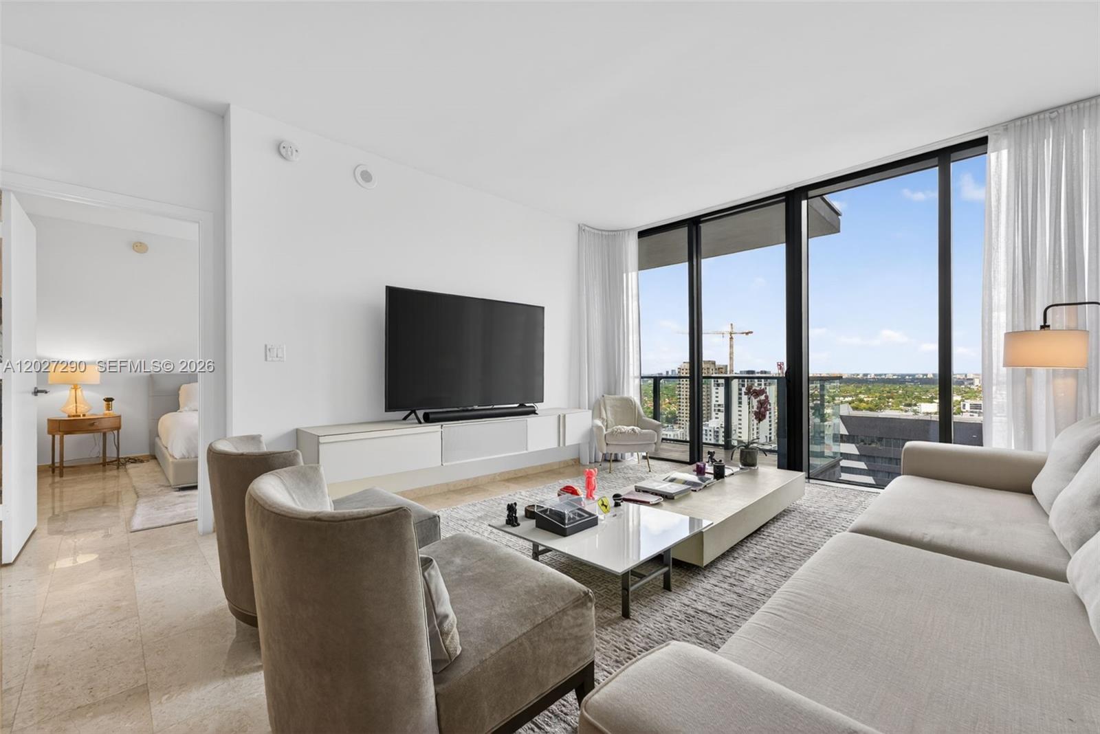 A modern living room features a wall-mounted television, neutral furniture, and floor-to-ceiling windows — 88 SW 7th St # 2408, Miami FL 33130, MIAMI, FL