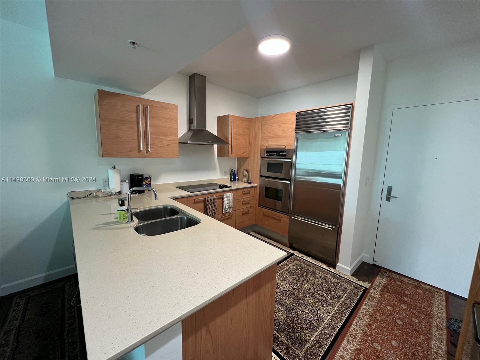 A kitchen features light wood cabinets, stainless steel appliances, and a quartz countertop island — 218 SE 14th Street # 1806, Miami FL 33131, MIAMI, FL
