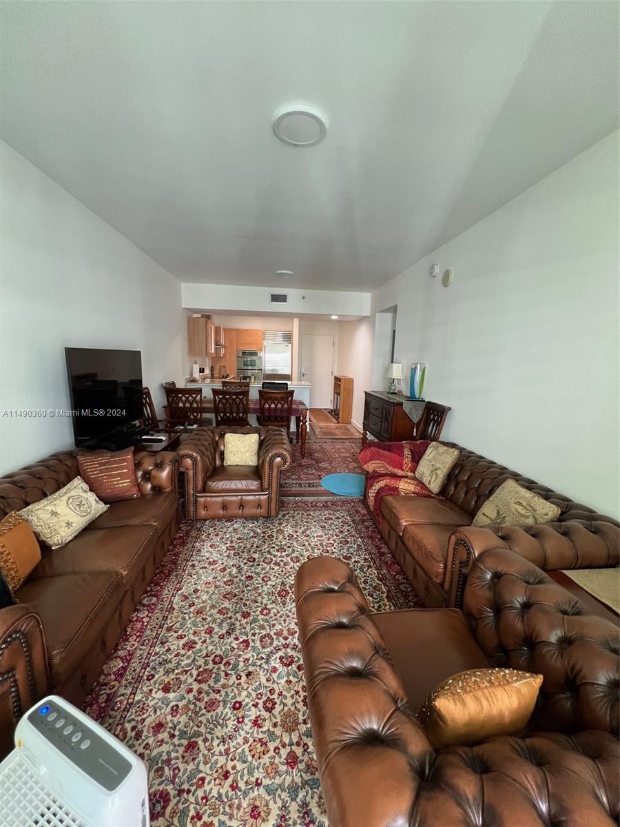 A living room features brown tufted leather sofas, a patterned area rug, and a dining area — 218 SE 14th Street # 1806, Miami FL 33131, MIAMI, FL