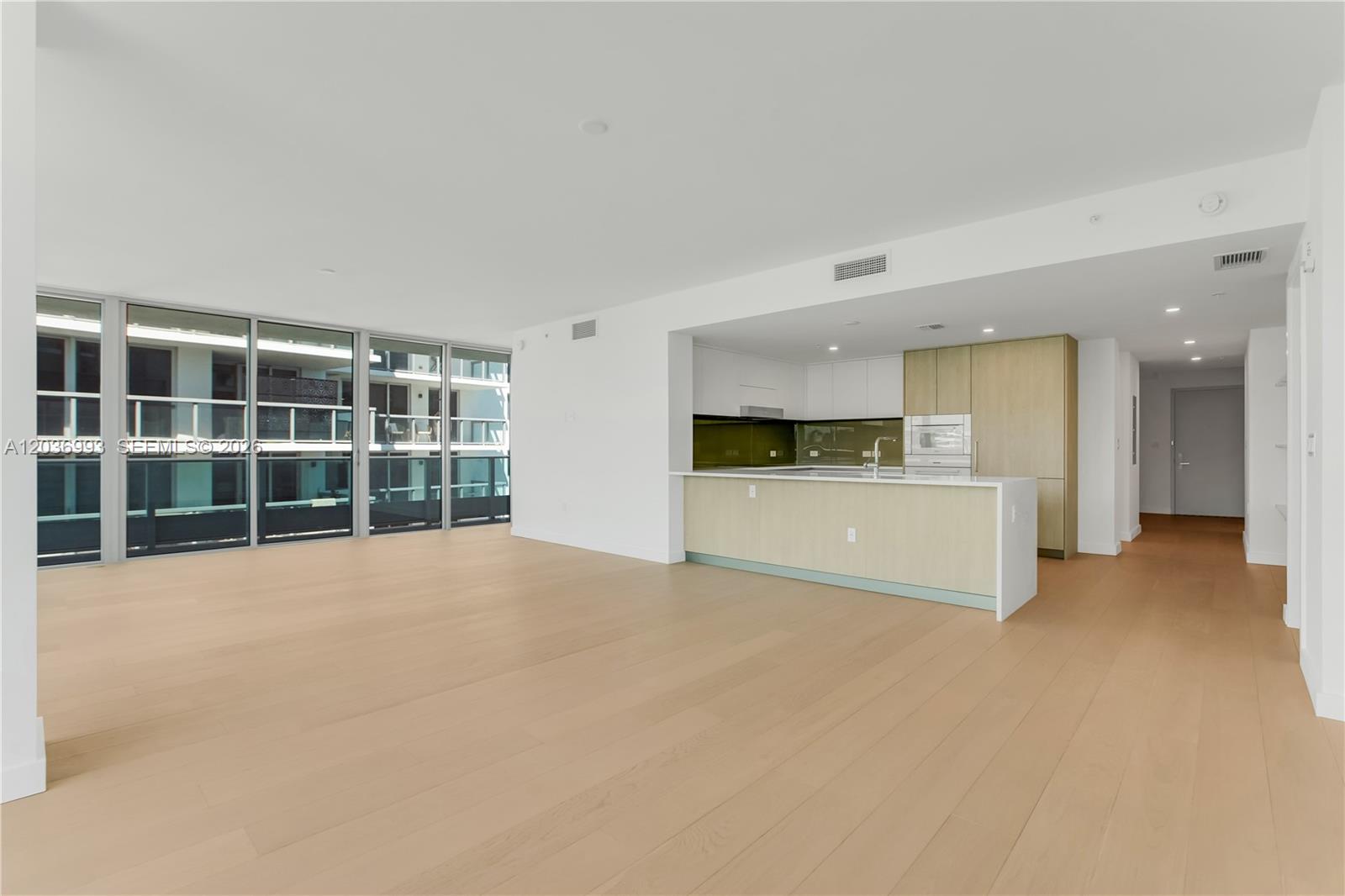An open-concept living area features light wood flooring, a modern kitchen, and floor-to-ceiling windows — 9221 E Bay Harbor Drive # 512, Bay Harbor Islands FL 33154, BAY HARBOR ISLANDS, FL