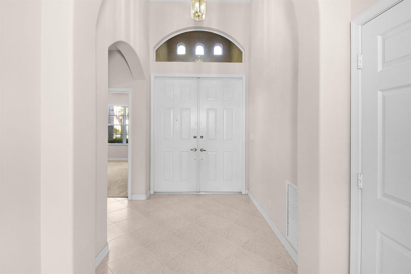 A bright entryway features a double front door, arched ceiling, and light-colored tile flooring — 7084 SE Cricket Court, Stuart FL 34997, STUART, FL
