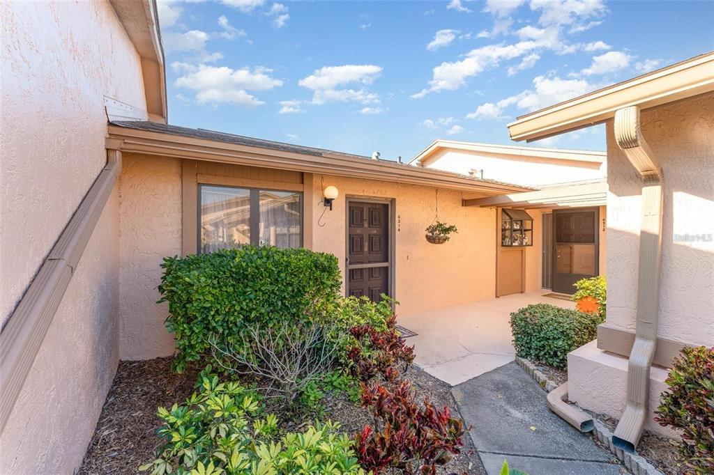 A tan stucco exterior features a front entryway with a screen door and landscaping — 6314 29TH AVENUE W, BRADENTON, FL