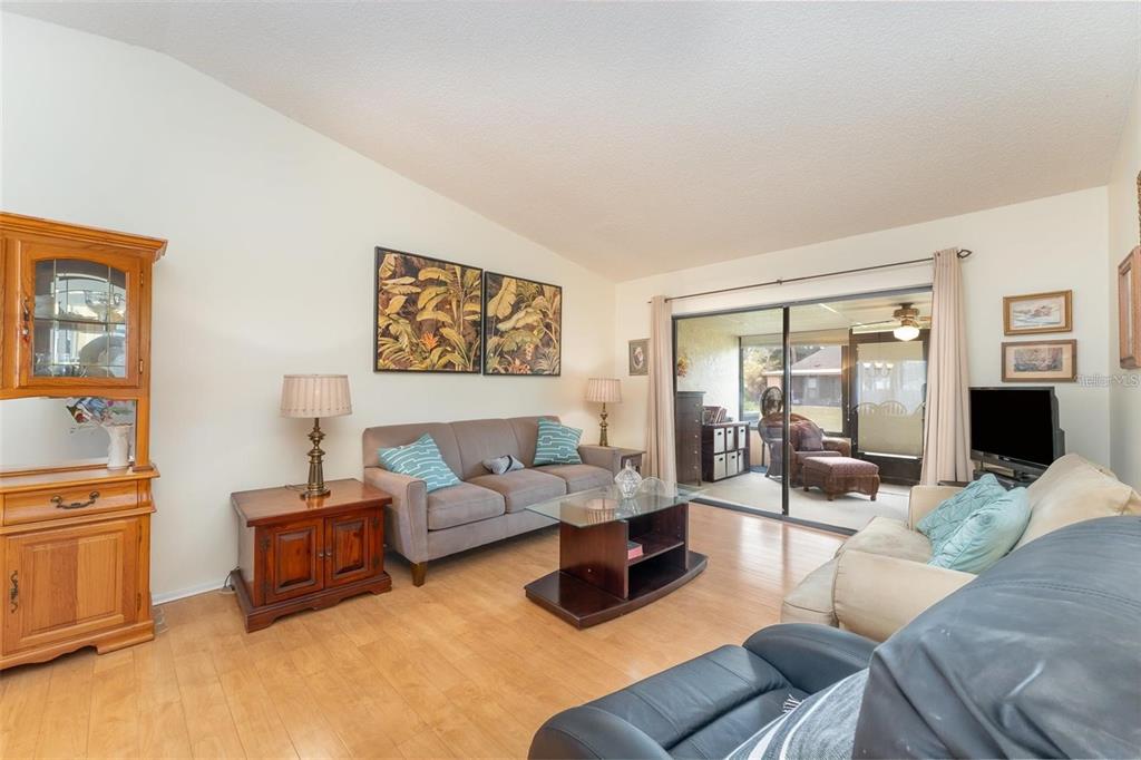 A living room features light wood flooring, a gray sofa, and a glass-topped coffee table — 6314 29TH AVENUE W, BRADENTON, FL