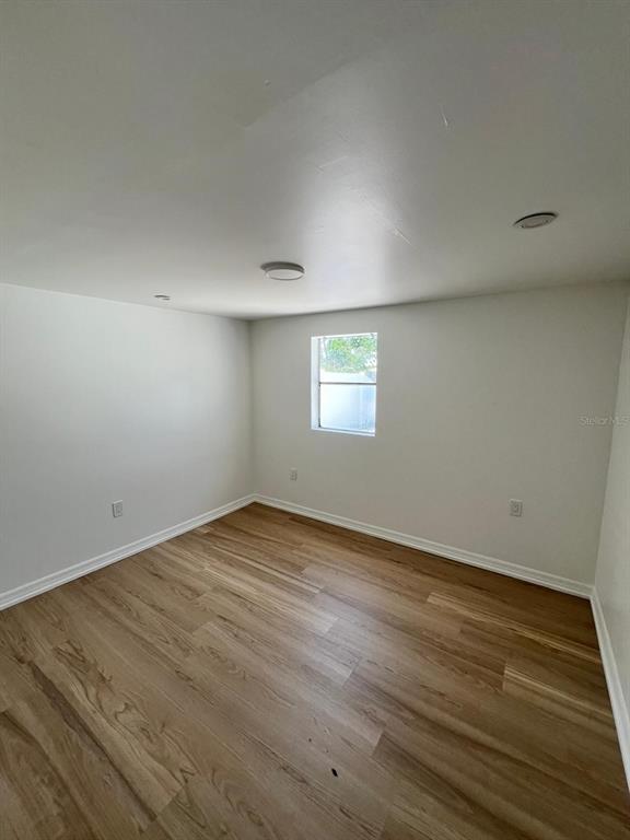 An empty bedroom features light wood-look flooring, white walls, and a single window — 901 PADUA COURT, NOKOMIS, FL