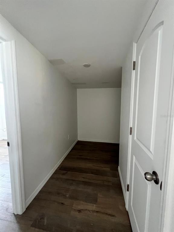 A narrow hallway with wood-look flooring leads to a small, empty room — 901 PADUA COURT, NOKOMIS, FL