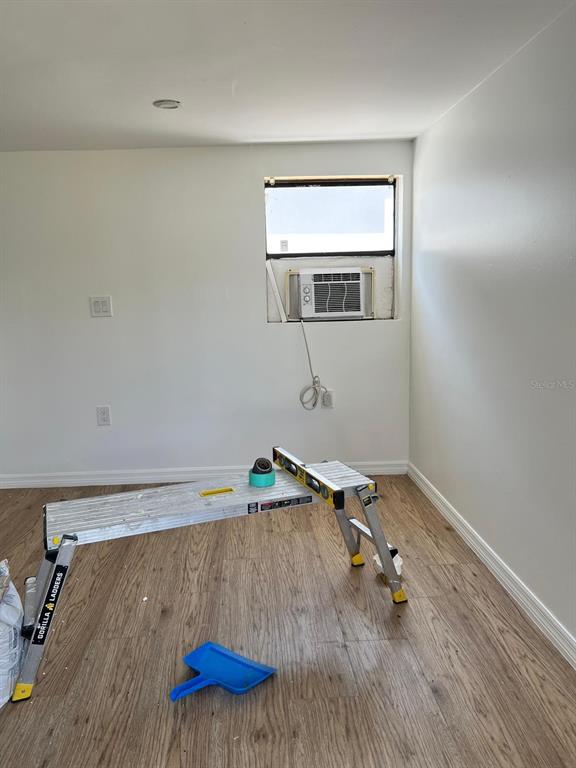 An interior room features light wood-look flooring, white walls, and a window-mounted air conditioning unit — 901 PADUA COURT, NOKOMIS, FL