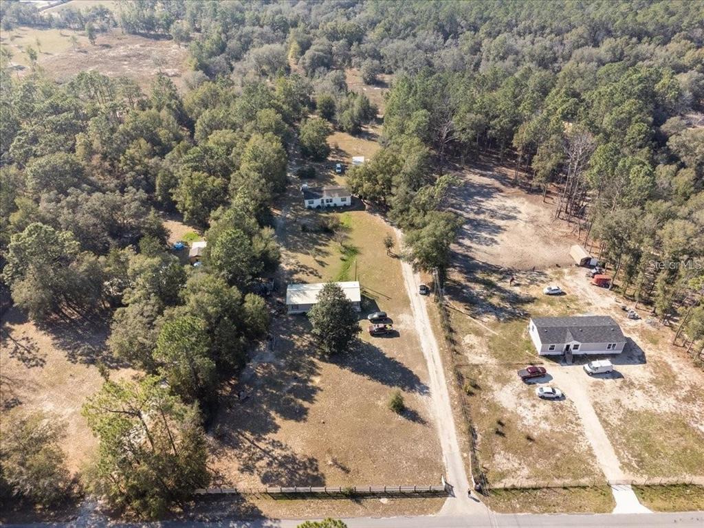 An aerial view shows multiple houses on a large, wooded lot with a dirt driveway — 3230 SW 189TH AVENUE, DUNNELLON, FL