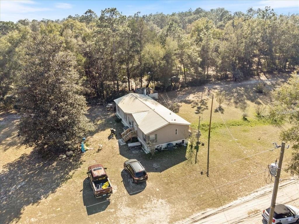 An aerial view of a tan manufactured home with a metal roof on a wooded lot — 3230 SW 189TH AVENUE, DUNNELLON, FL