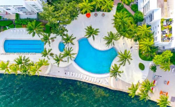 An aerial view shows a swimming pool area with palm trees next to a body of water — 750 NE 64th St # B316, Miami FL 33138, MIAMI, FL