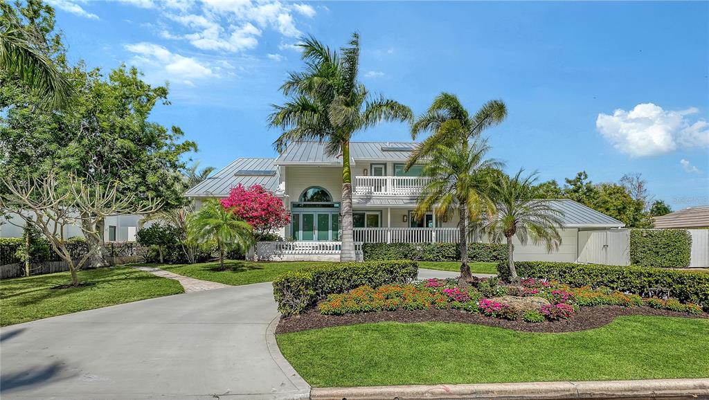 A two-story house with a metal roof, palm trees, and a landscaped front yard — 476 MEADOW LARK DRIVE, SARASOTA, FL